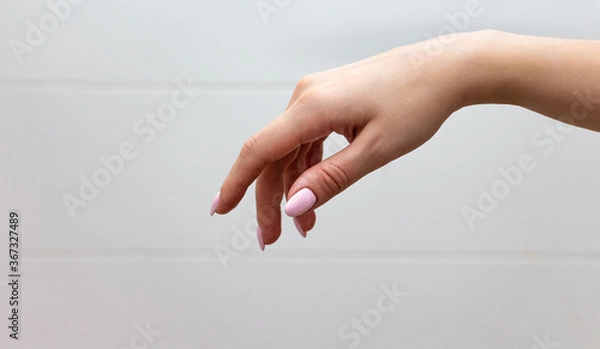 Obraz A well-groomed female hand with a neat manicure hanging smoothly in the air on a light background.