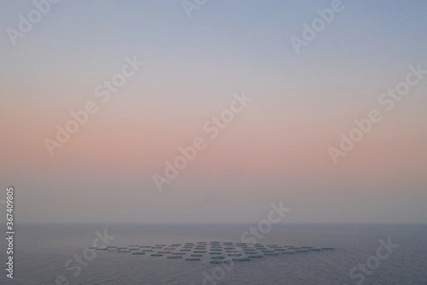 Obraz sunrise in the sea with fog and a formation of shapes in the water in long distance