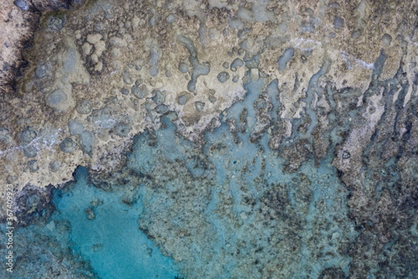 Obraz An aerial view of the beautiful Mediterranean sea, where you can see the rocky textured underwater corals and the clean turquoise water of Cyprus
