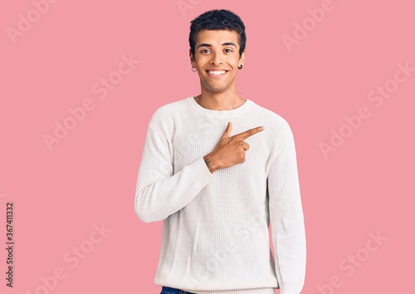 Fototapeta Young african amercian man wearing casual clothes cheerful with a smile on face pointing with hand and finger up to the side with happy and natural expression