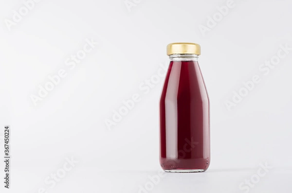 Fototapeta Violet berries juice in glass bottle with gold cap and white blank label mock up on white background with copy space, template for packaging, advertising, design product, branding.