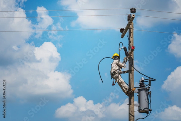 Fototapeta Lineman climb concrete pole are installing hotline-clamps to the ends of insulated electrical cables. To prepare for the installation of a single phase transformer into a high voltage distribution.