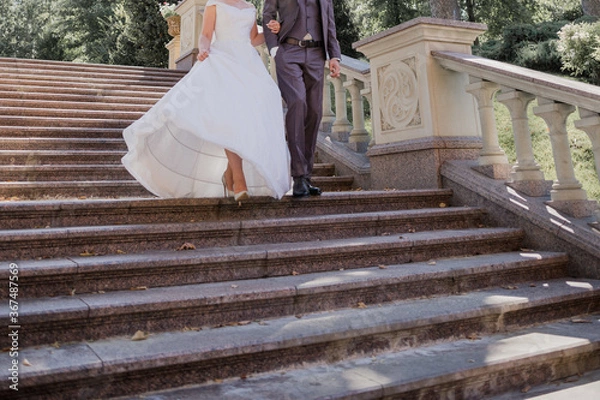 Fototapeta groom with bride on stairs near the building