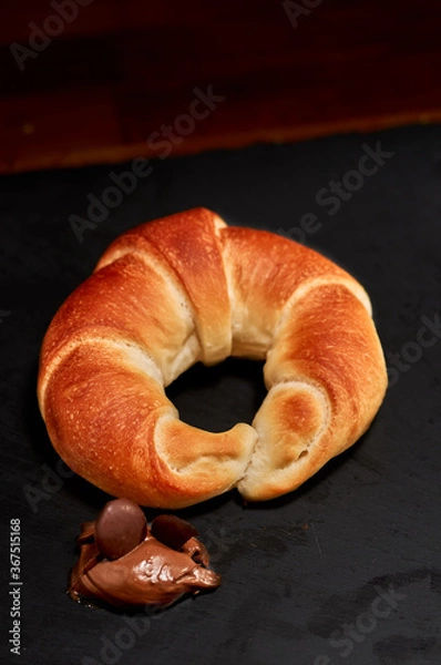 Fototapeta Freshly made rolled bun with chocolate on black stone cutting board. Very shallow depth of field