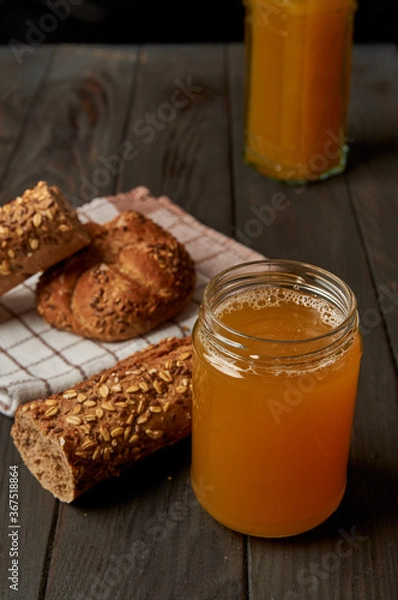 Fototapeta Kvass drink in a glass jar on an old wooden board with rye bread 
