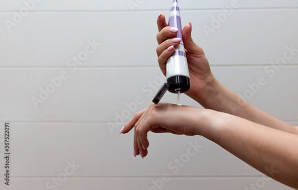Obraz Close up of well-groomed female hands with a tube of cosmetic on the white tile background. Skincare and handcare concept. Cosmetic procedure.