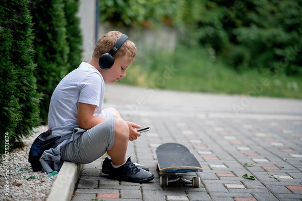 Fototapeta Child playing with mobile phone and listening music in backyard