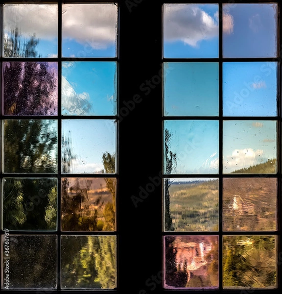 Fototapeta A window with multi-colored glass that overlooks a park or garden