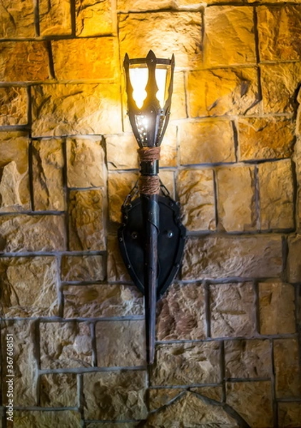 Fototapeta An old torch burns on a stone wall in an castle