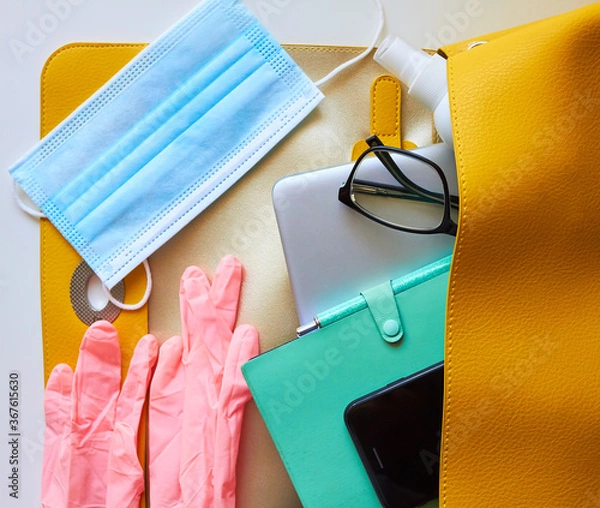 Fototapeta return to work, to office, to university, to study.new rules after covid-19. open women's bag: disposable gloves, protective mask, antiseptic, smartphone, notepad, glasses, laptop, wallet.