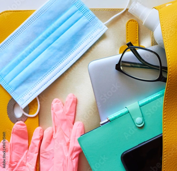Fototapeta return to work, to office, to university, to study.new rules after covid-19. open women's bag: disposable gloves, protective mask, antiseptic, smartphone, notepad, glasses, laptop, wallet.