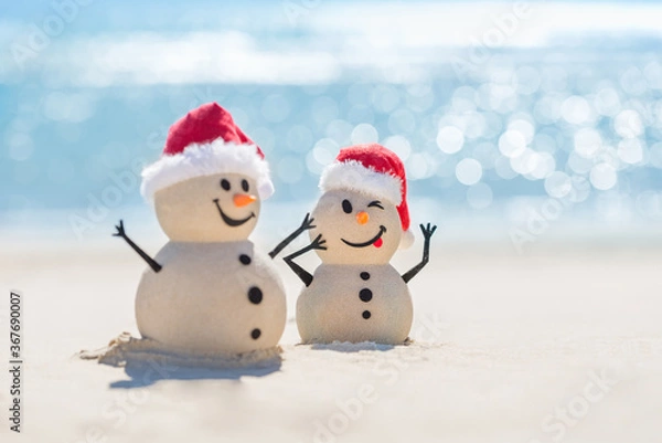 Obraz Two Sandy Christmas Snowmen are celebrating Christmas on a beautiful beach with beautiful bokeh in the background, one of them is only in focus