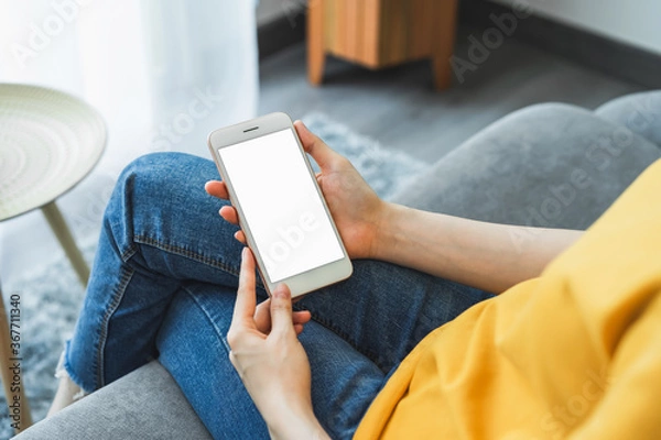 Fototapeta Woman hand holding smartphone and touching blank screen. Mockup of advertisement.