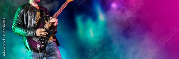 Fototapeta Gitarzysta występuje na scenie. Gitarzysta rockowy gra solo na gitarze elektrycznej. Artysta i muzyk występuje jak gwiazda rocka. Wersja czarno-biała. Wersja zielona i pruple. Obraz panoramiczny.