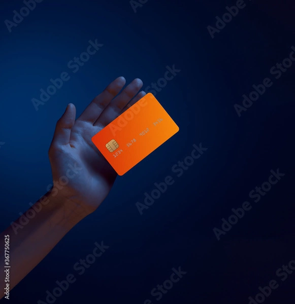Obraz Close up female hand holds levitating template mockup bank credit card with online service isolated on blue background