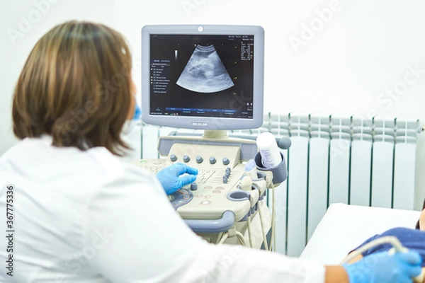 Obraz A person in a blue shirt, the girl is lying on the couch, she is given an ultrasound