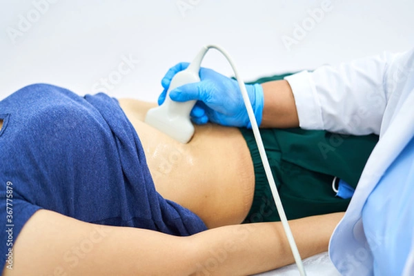 Obraz A person in a blue shirt, the girl is lying on the couch, she is given an ultrasound