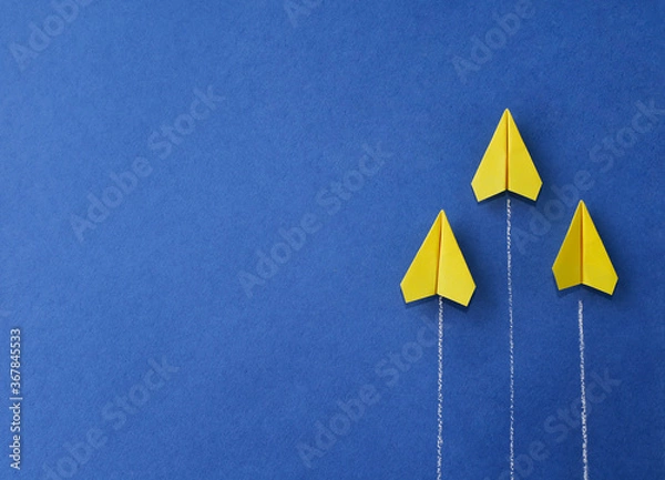 Obraz Yellow paper planes on a blue background. The concept of moving towards success. Upward movement.
