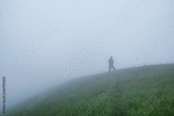 Fototapeta Silhouette of a man in dense fog in a mountainous area