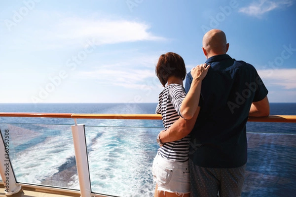 Obraz caucasian man and brunette woman in sunglasses traveling together on cruise ship,standing on balcony and enjoying with beautiful view of Caribbean sea