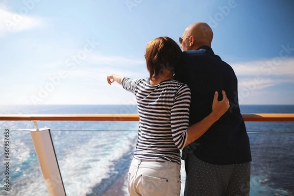 Obraz caucasian man and brunette woman in sunglasses traveling together on cruise ship,standing on balcony and enjoying with beautiful view of Caribbean sea