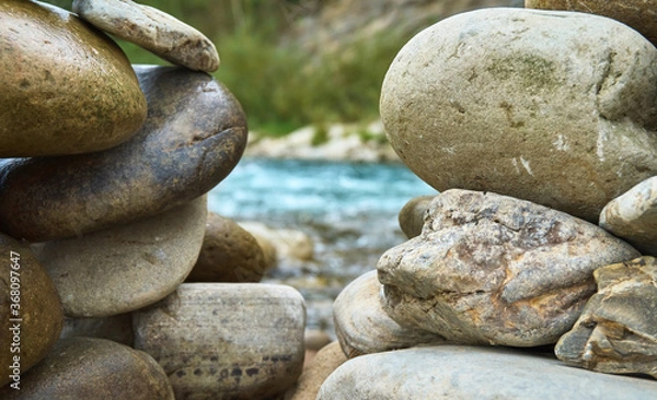 Obraz Stone cairn against the background of dark green water in. Stone balancing along the river.