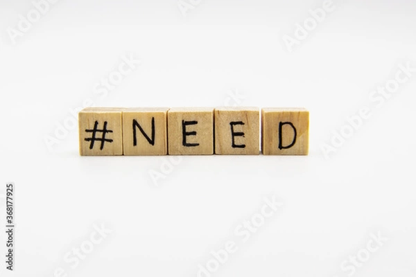Fototapeta A word NEED with hashtag. Wooden small cubes with letters isolated on white background with copy space available. Concept image with hashtag.