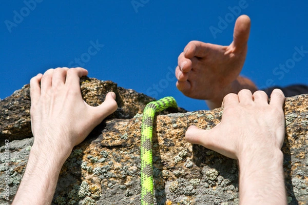 Fototapeta Rock climber reaching for helping-hand partner.