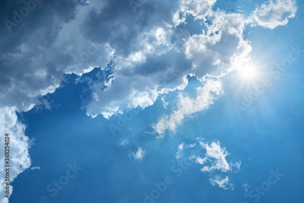 Obraz Radiant sun behind dark clouds in a blue sky
