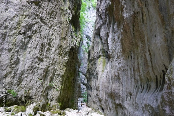Fototapeta person walking between high rocks on a riverbed
