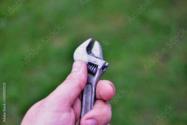 Fototapeta A small shiny wrench in the hands of the master