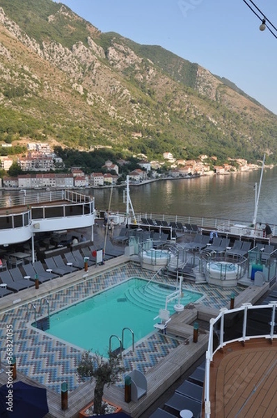 Fototapeta The deck of a cruise ship with a swimming pool and sun beds, against the backdrop of the Adriatic sea off the coast of Montenegro.