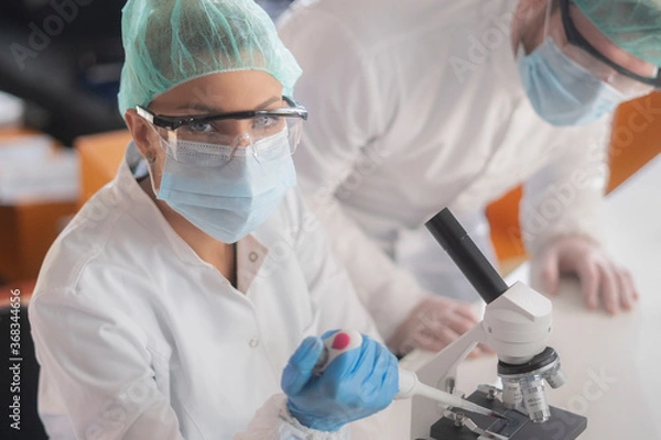 Fototapeta A close-up of a female doctor or medical researcher wearing protective gear, mask and face shield in a laboratory.