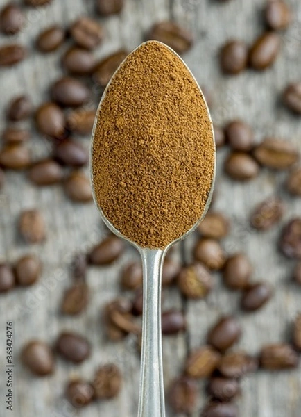 Fototapeta A close up of a spoonful of instant coffee powder over coffee beans