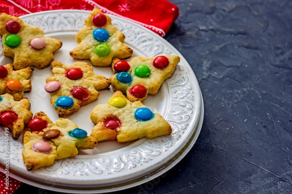 Fototapeta Colorful christmas homemade christmas tree cookies on white plate on dark background, copy space