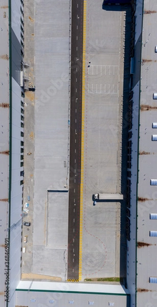 Fototapeta Aerial view of goods warehouse. Logistics center in industrial city zone from above. Aerial view of trucks loading at logistic center stock photo