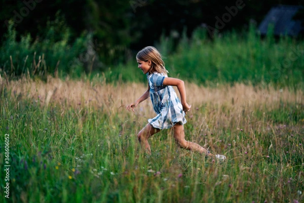 Obraz A girl chasing a butterfly in a flower meadow.  Shot at Holmenkollen, Oslo, Norway.