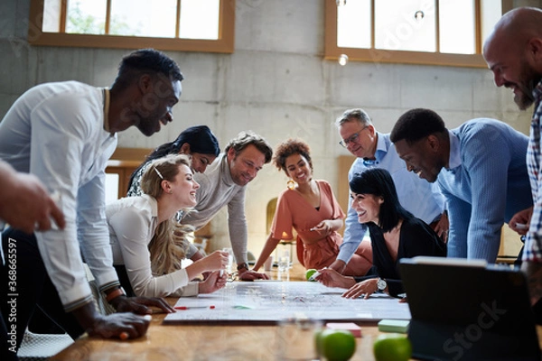 Obraz Happy multiethnic professionals discussing while planning strategy at conference table during meeting in creative workplace