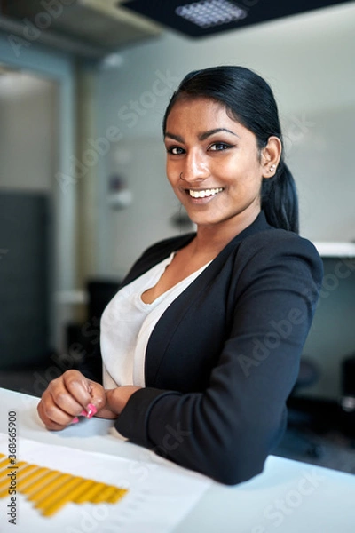 Obraz Portrait of smiling young female design professional at desk working in creative office