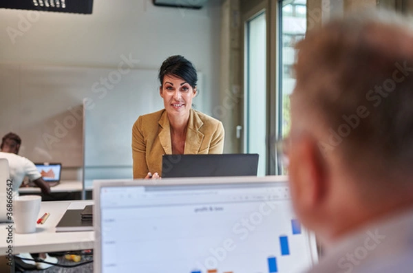Obraz Smiling businesswoman discussing with businessman while working at creative office