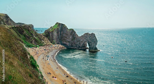 Fototapeta Durdle Door, Jurassic Coast near Lulworth in Dorset, England - a natural limestone arch. Durdle Door with people relaxing on the beach on a sunny day in August 2020.