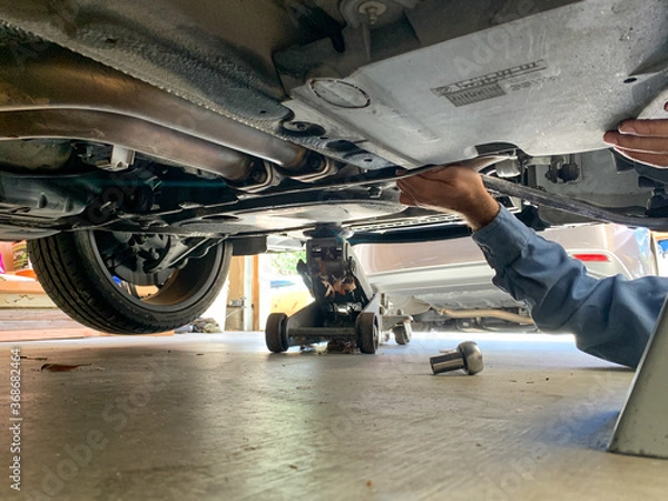 Fototapeta Mechanic Under Car with Loose Bolt