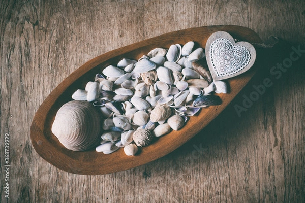 Fototapeta Still life with seashells in a wooden bowl on an old cracked table
