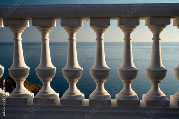 Fototapeta Classic balustrade on the embankment against the sea. White balcony over the sea. Promenade with a beautiful view of the sea on a clear day. Close-up of the balustrade by the sea