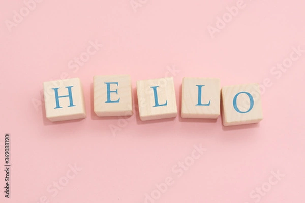 Fototapeta The word HELLO is made of wooden cubes on a pink background.