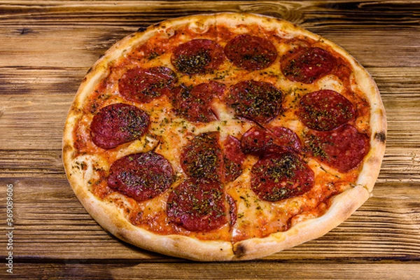 Fototapeta Pizza with salami sausage and parmesan cheese on a wooden table