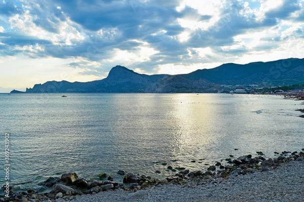 Fototapeta View of the sea and mountains from the shore at sunset