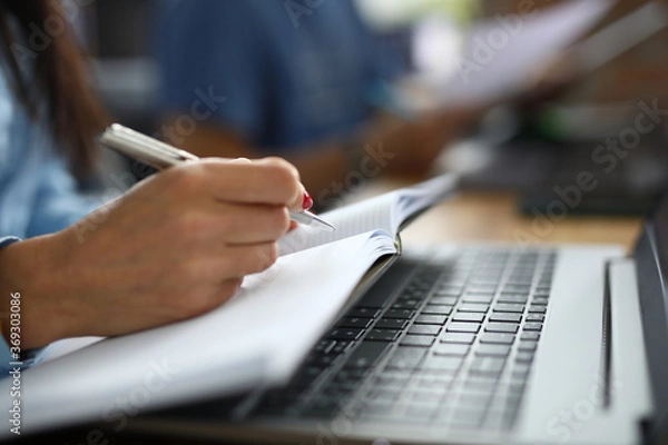 Obraz Female hand holds pen with notebook. Copywriting courses for beginners concept