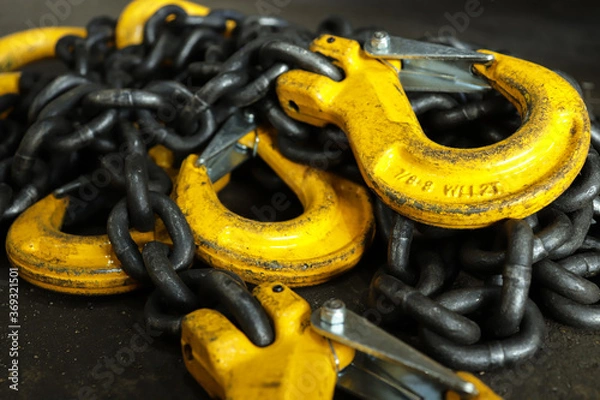 Obraz Iron chains with hooks lie on the floor of the workshop. A device for loading and unloading goods.