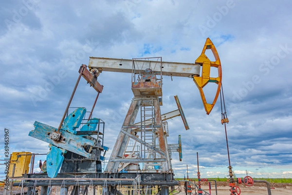 Obraz Petroleum concept. Oil pump rig. Oil and gas production. Oilfield site. Pump Jack are running. Drilling derricks for fossil fuels output and crude oil production. Global crisis. War on oil prices.